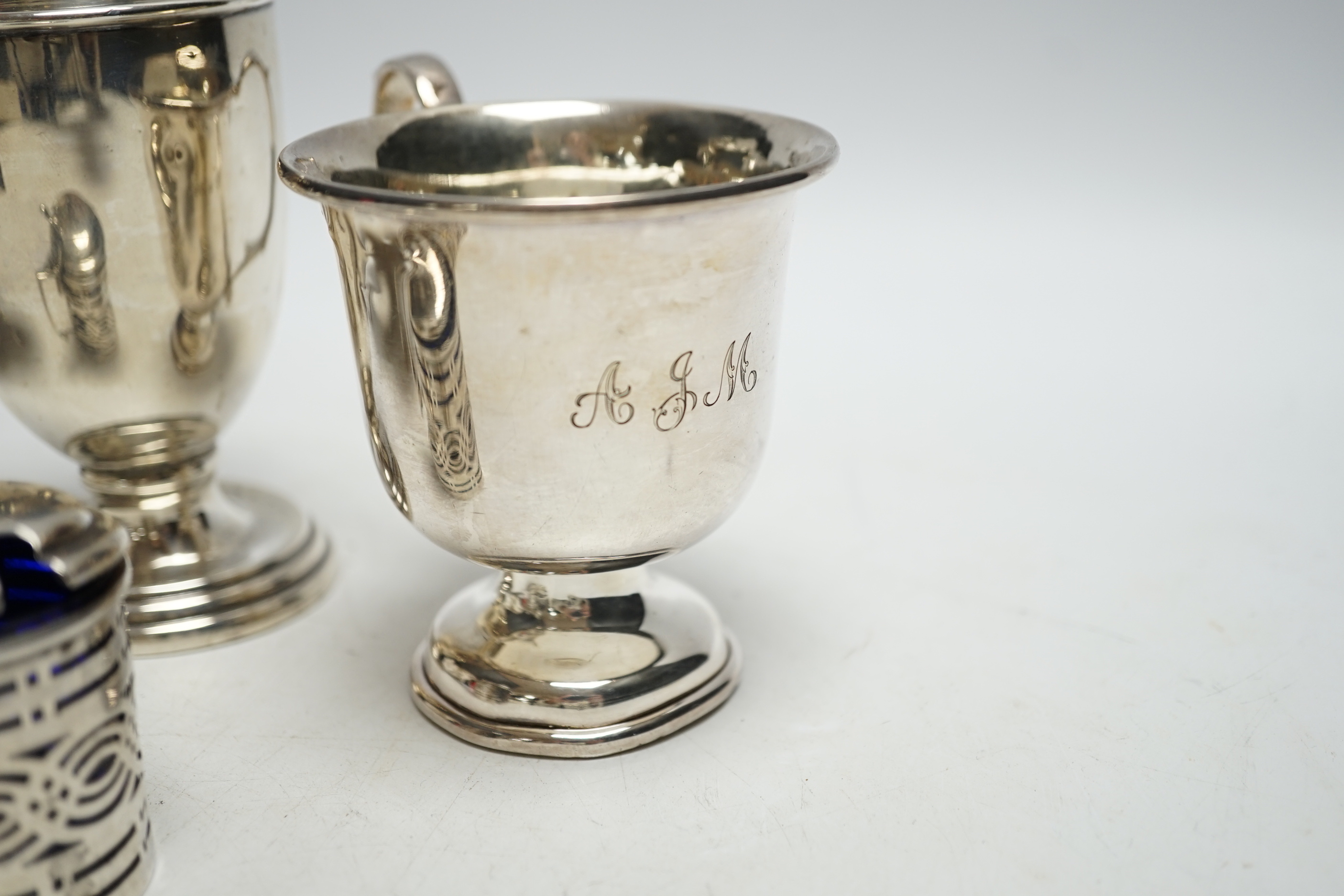 Four pieces of George V silver:- a sauceboat, a mustard pot, a vase and a cup.